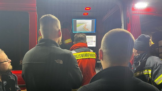 Einsatzkräfte der Freiwilligen Feuerwehr besprechen die Hochwasser-Lage an einem Bildschirm. © NDR Foto: Anna-Lou Beckmann