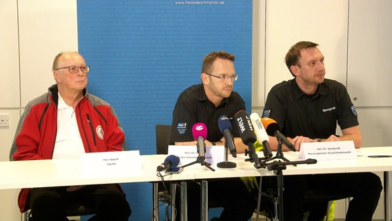 Michael Ippich, DGzRS, Robby Renner, head of the accident command and Benedikt Spanghardt, press spokesman for the accident command at the press conference on the occasion of a ship accident in the North Sea.  © Emergency Command 