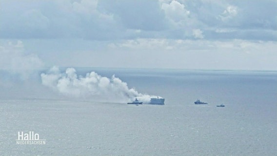 Smaller ships approach a burning container ship.  © Screenshot 