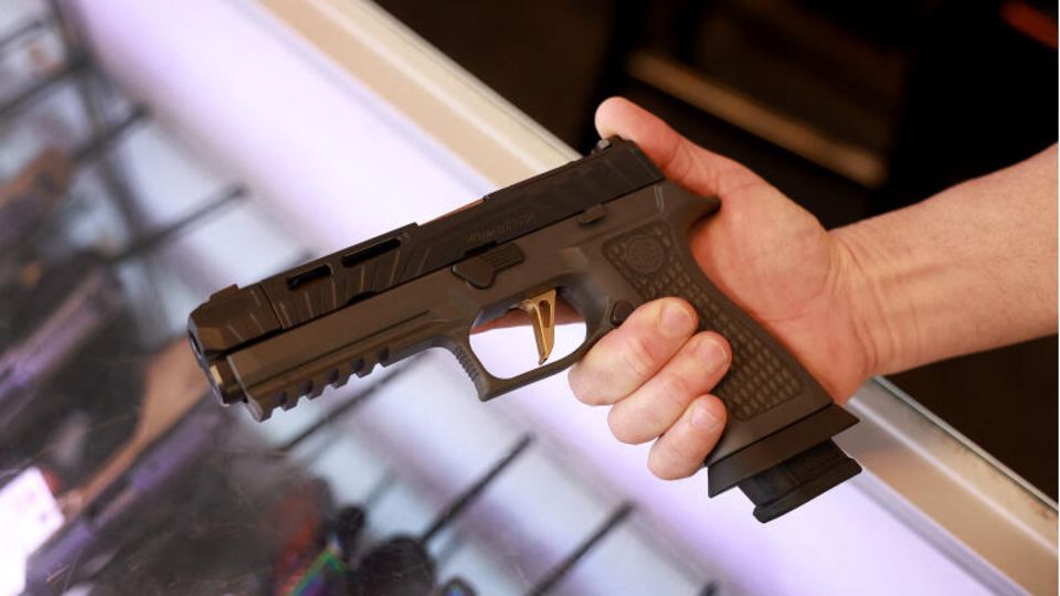 A man holds a Sig Sauer P320 handgun.  Carrying guns in public is legal in Missouri