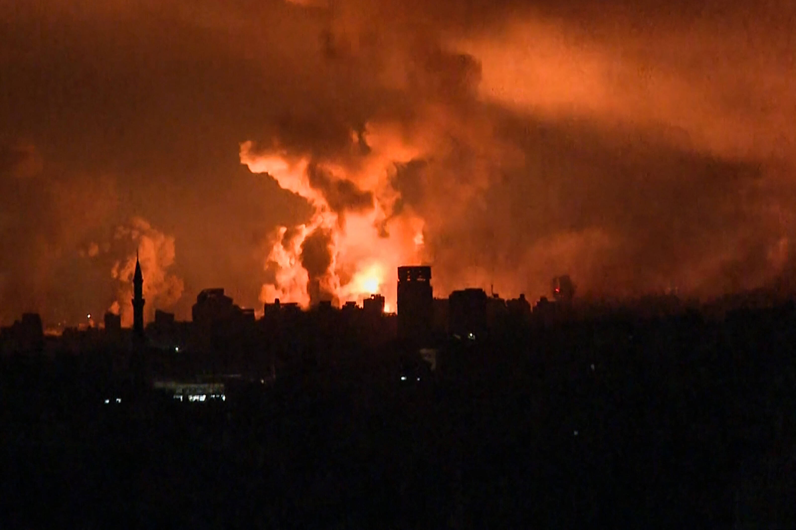 Cette image tirée d'une séquence TV de l'AFP montre des boules de feu s'élevant au-dessus de la ville de Gaza lors d'une frappe israélienne le 27 octobre 2023, alors que les batailles entre Israël et le mouvement palestinien Hamas se poursuivent. — © - / AFP
