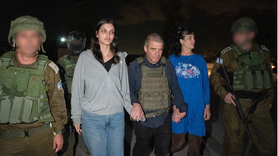 Two women walk between soldiers - they are the two hostages released by Hamas, Judith and Natalie Raanan