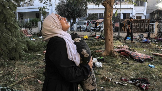 Trip to Israel: A grieving woman stands with a pillow in front of the hit Ahli Arab Hospital in Gaza.