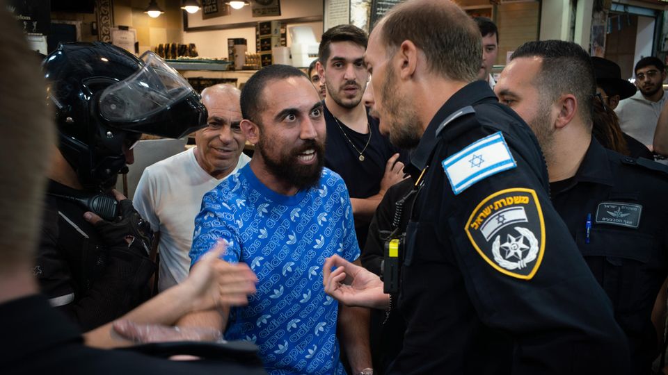Dispute at the Yehuda Market in Jerusalem: A seller is escorted from the market by police after a commotion
