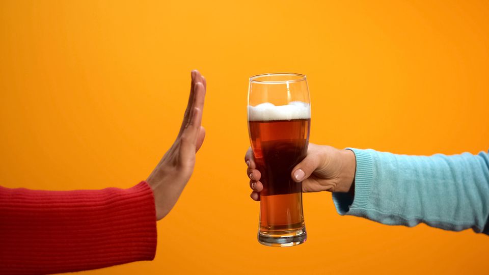 A hand rejects a glass of beer