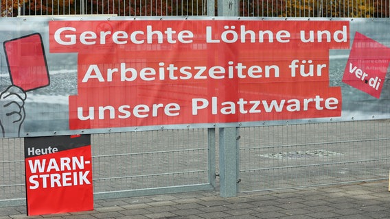 Posters and banners hang on the fence at a sports field in Hamburg during a warning strike by sports field attendants.  The demand is written on a banner "Fair wages and working hours for our groundskeepers".  © picture alliance / dpa Photo: Bodo Marks