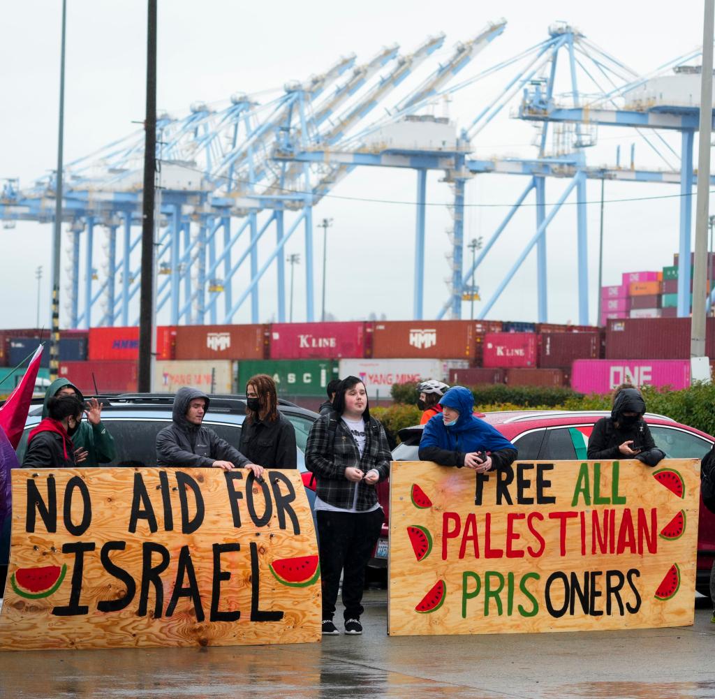 Demonstranten halten große Holzschilder hoch, während sie den Haupteingang des Hafens von Tacoma blockieren