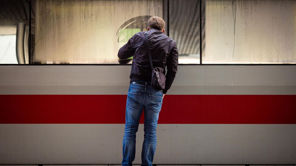 A man looks into an ICE train standing on the platform