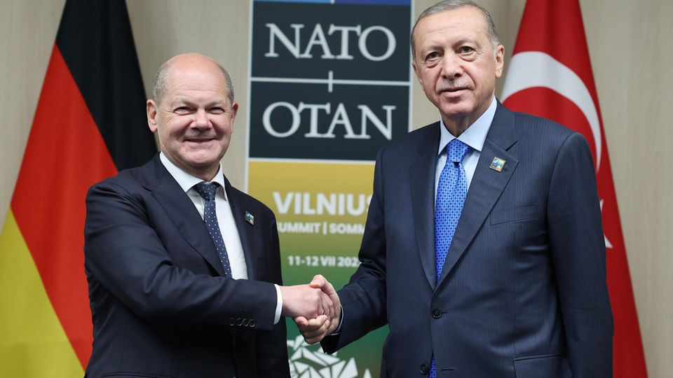 Olaf Scholz and Erdogan shake hands and look into the camera