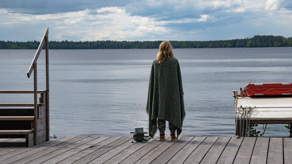 Eine Frau steht auf einem Steg am See.
