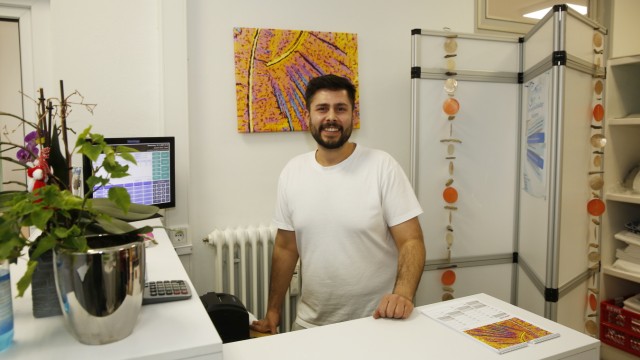 From Geretsried business life: Mustafa Omid is an employee of the sustainable laundry.  Behind him hangs a picture of Otto Rothe, who photographed cleaning products under a microscope in polarized light and is currently exhibiting at the Quartierstreff on Johannisplatz.