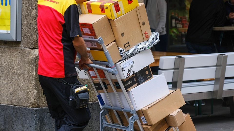 Parcel delivery man pushes many packages in front of him on hand trucks