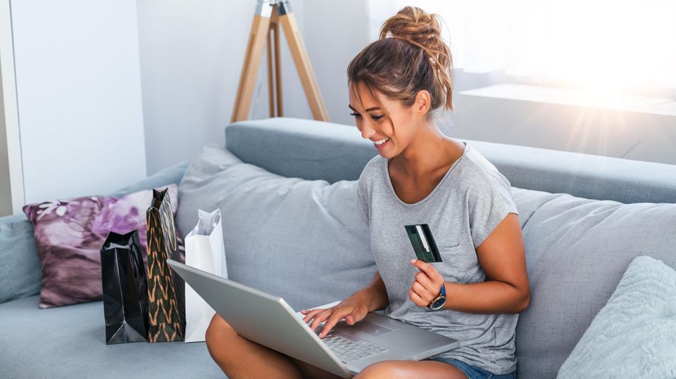 A woman sits on the sofa and shops online.