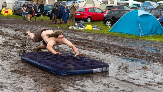 Festival visitor Benedikt jumps onto an air mattress in the mud at the Wacken Open Air 2017.  © dpa / picture alliance Photo: Christophe Gateau