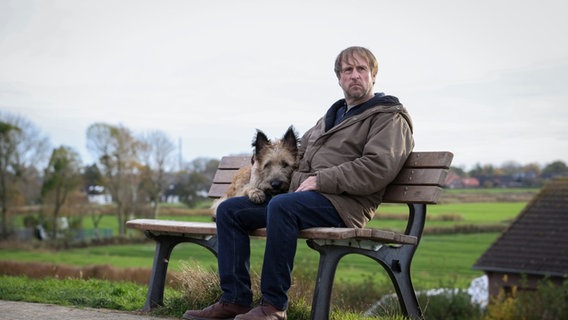 Sörensen (Bjarne Mädel) sits on a bench with his dog.  © NDR Photo: Michael Ihle