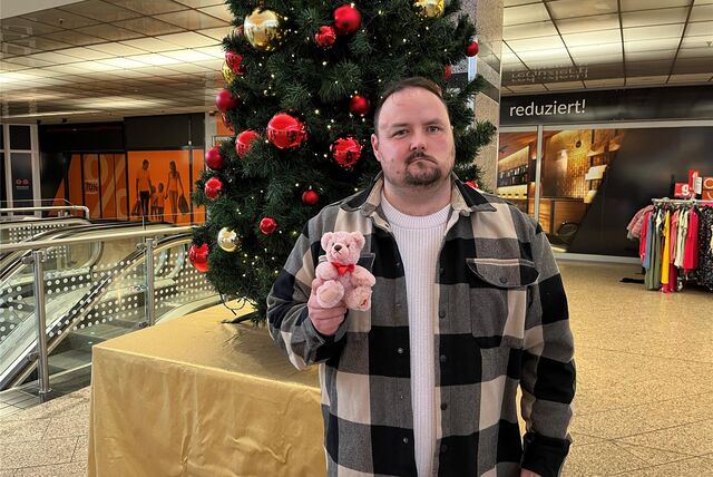 Pierre Barth holds a pink teddy bear in his hand and stands in front of a Christmas tree in Marler Stern.