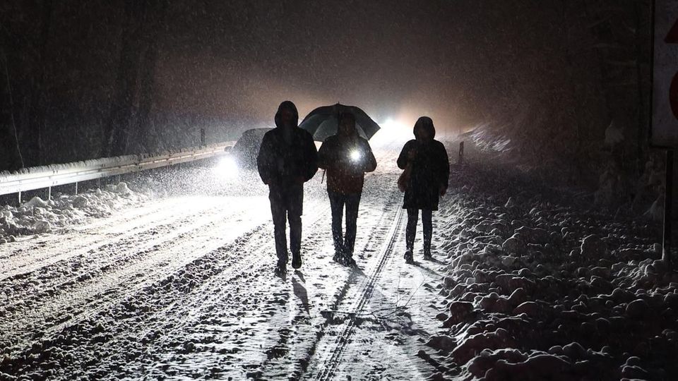 People walk on a snowy street at night