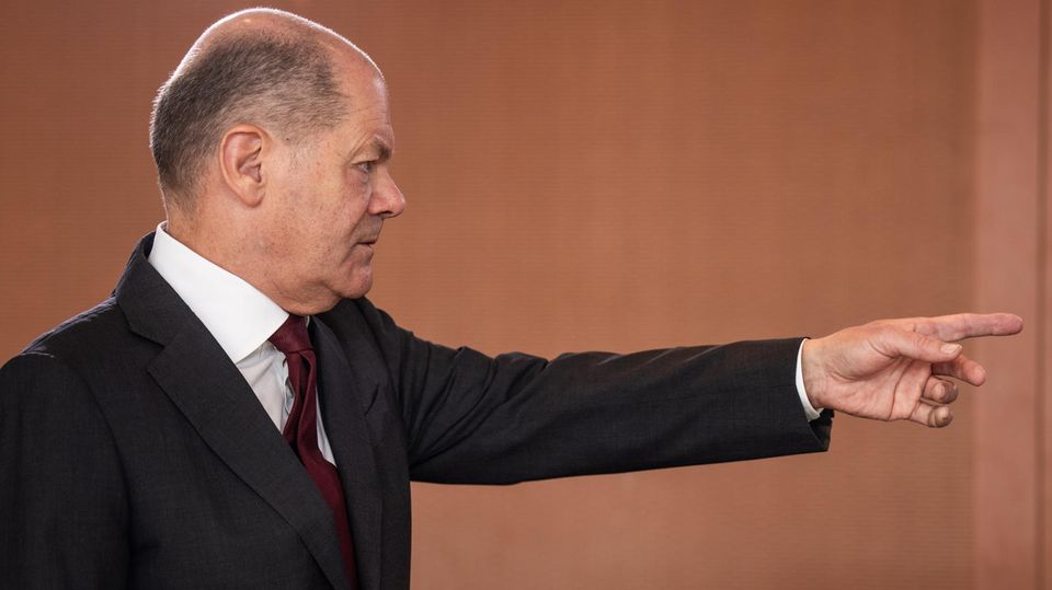Olaf Scholz points in one direction with his index finger outstretched