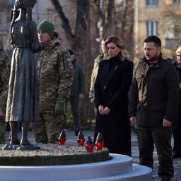 Volodymyr Zelenskyj and Olena Zelenska stand in front of a monument