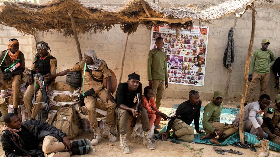Hunters wait in front of the Emir's house.  Nigeria's army uses their knowledge of the bush to hunt down the Islamists