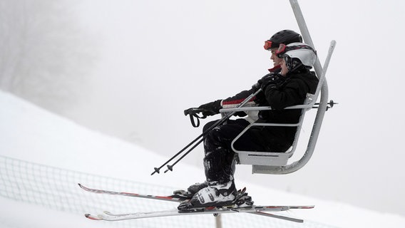 Winter sports enthusiasts sit with skis in the lift on Matthias-Schmidt-Berg near St. Andreasberg in the Harz Mountains.  © dpa-Bildfunk Photo: Swen Pförtner/dpa