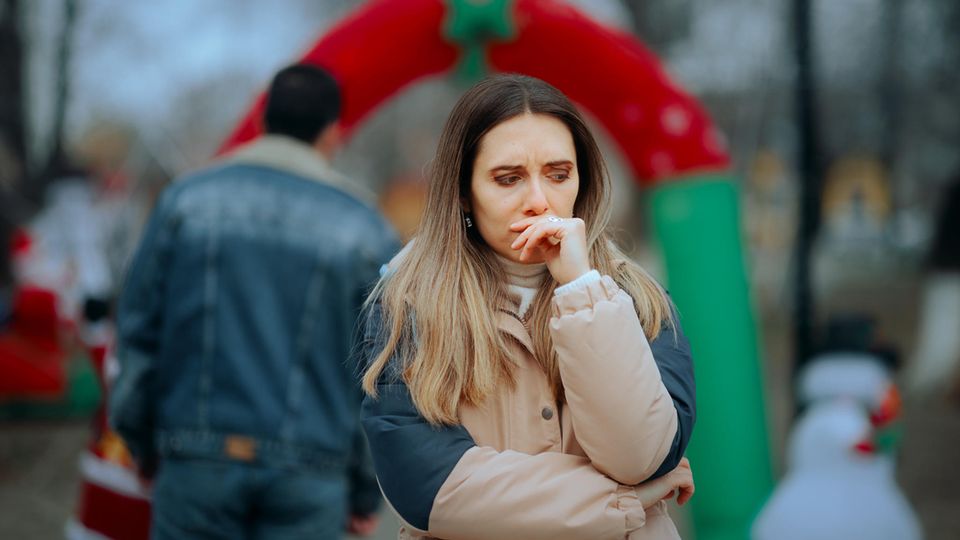 A woman wears a jacket and looks sad