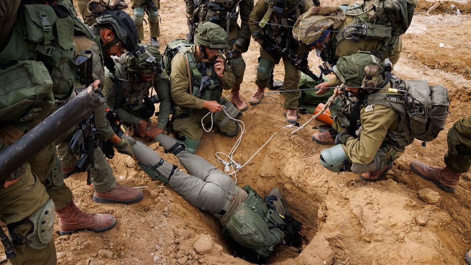 An Israeli soldier crawls into the entrance of a Hamas tunnel to set explosives