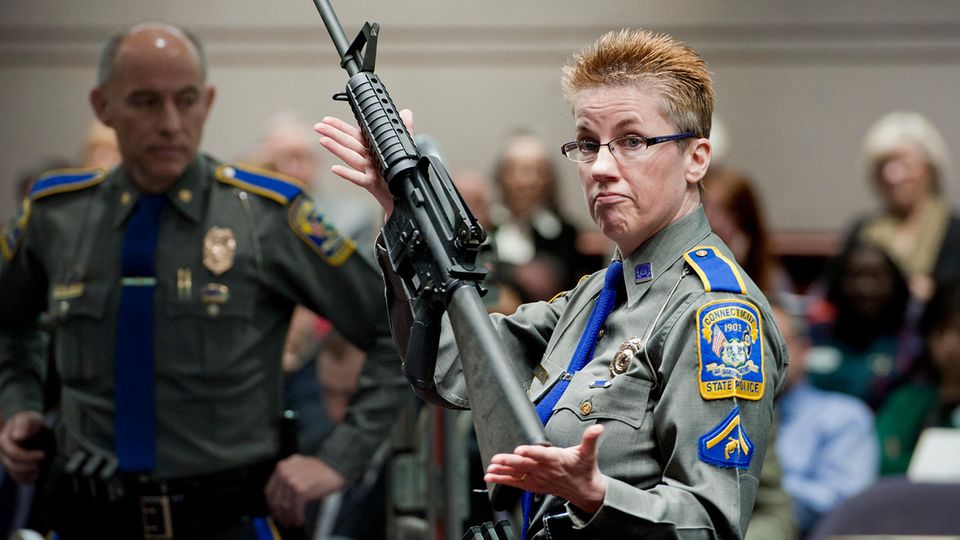 A police officer presents a Bushmaster AR-15.  Adam Lanza used such a weapon to kill his victims