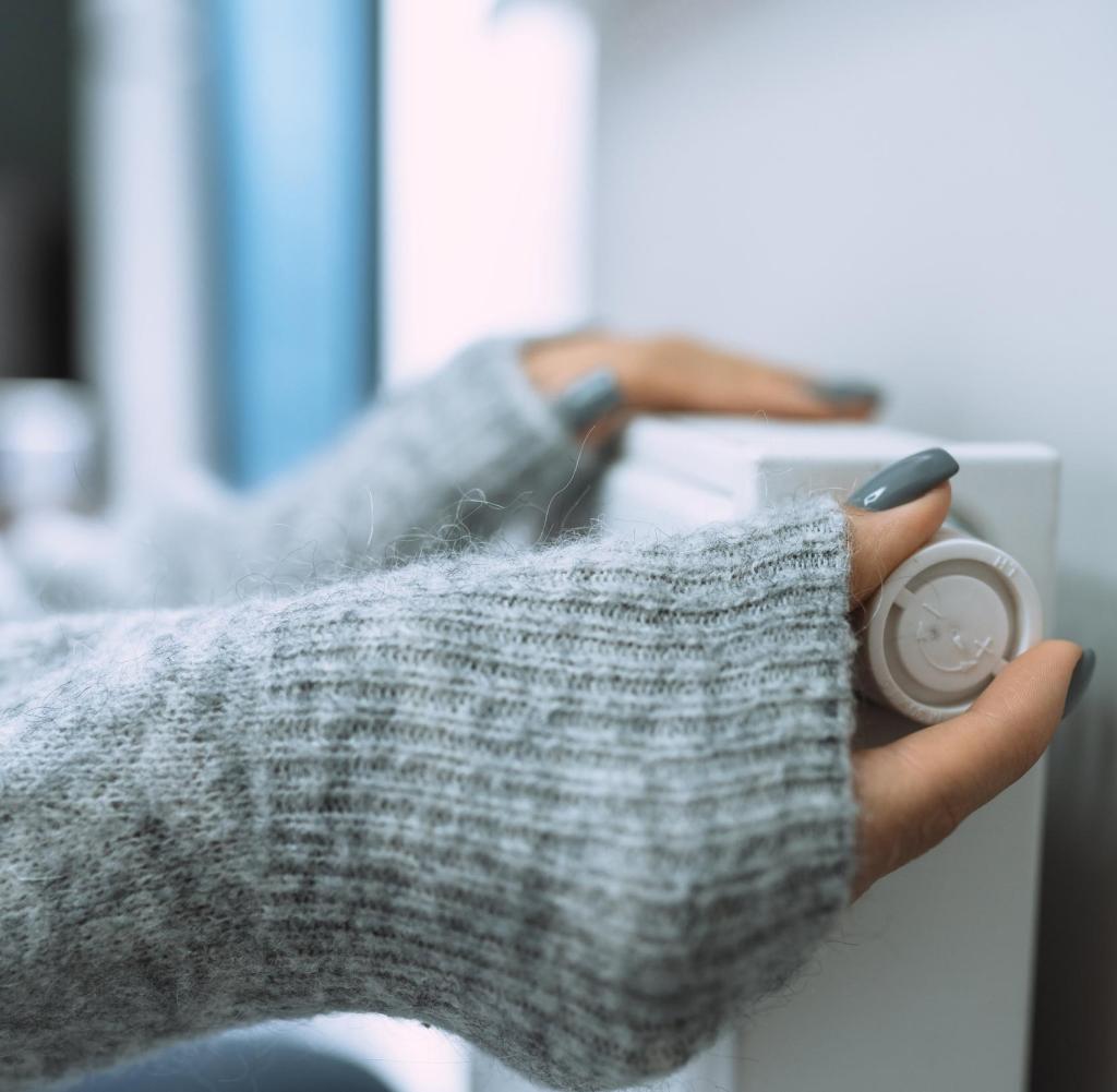 Unrecognizable woman hands in gray sweater touching and setting radiator thermostat regulator Getty ImagesGetty Images