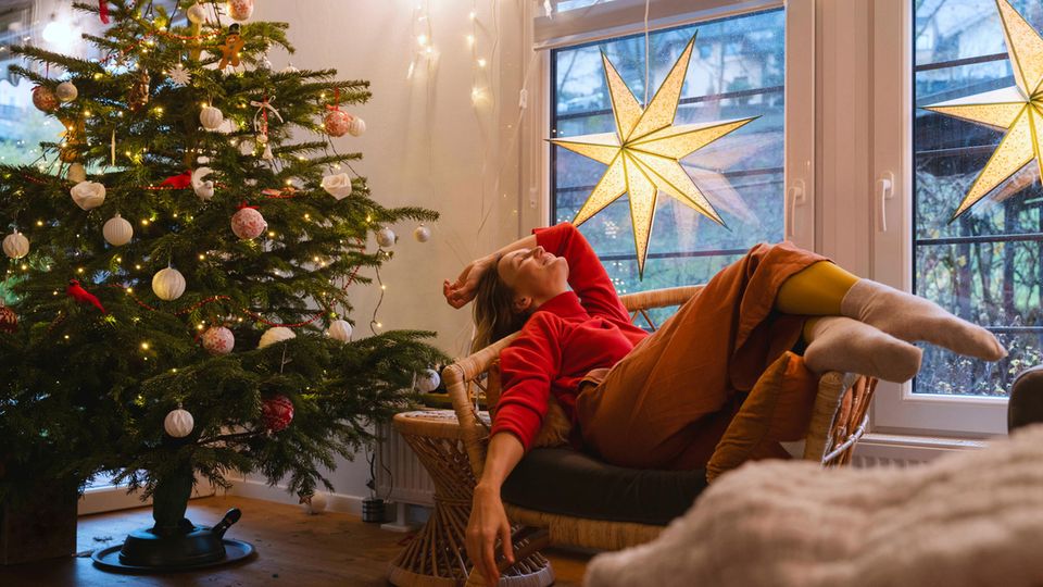 Advent: A room decorated for Christmas with a Christmas tree and a woman relaxing on an armchair