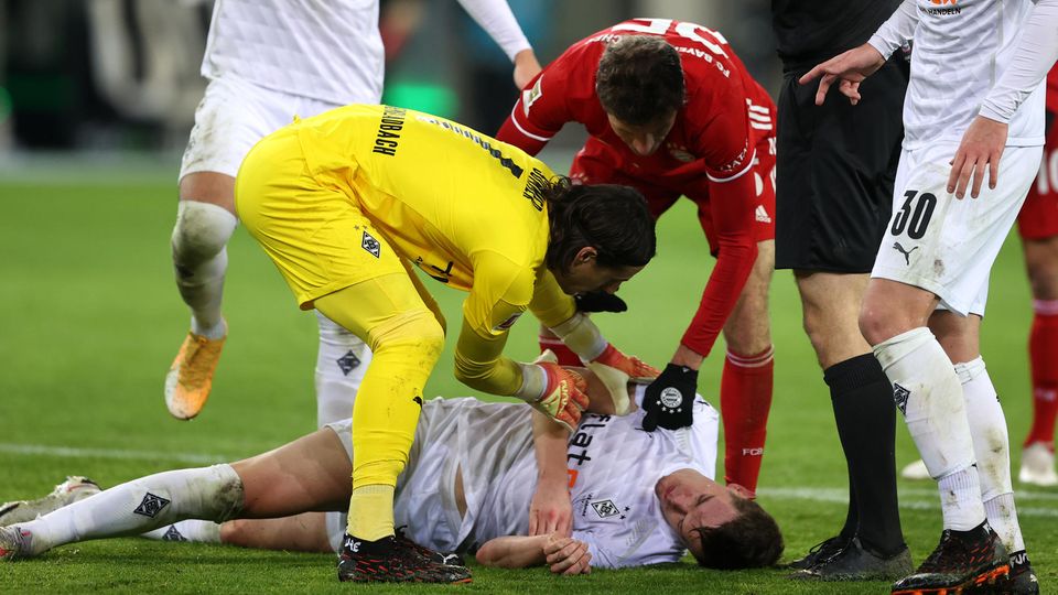Gladbach defender Matthias Ginter lies dazed on the ground after being hit in the head