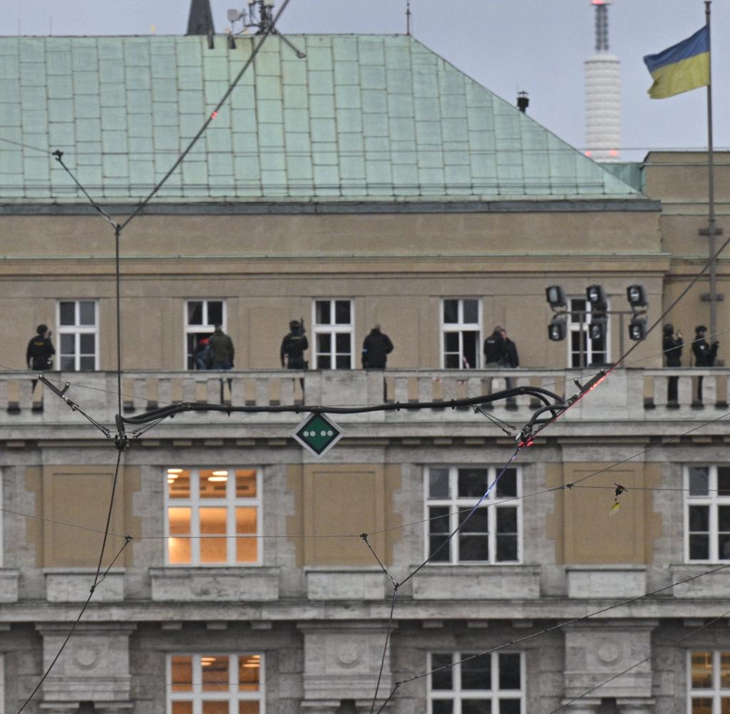Police officers stand on the roof of the Faculty of Arts building