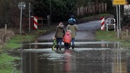 Eine Familie läuft über eine überschwemmte Straße. © NonstopNews 