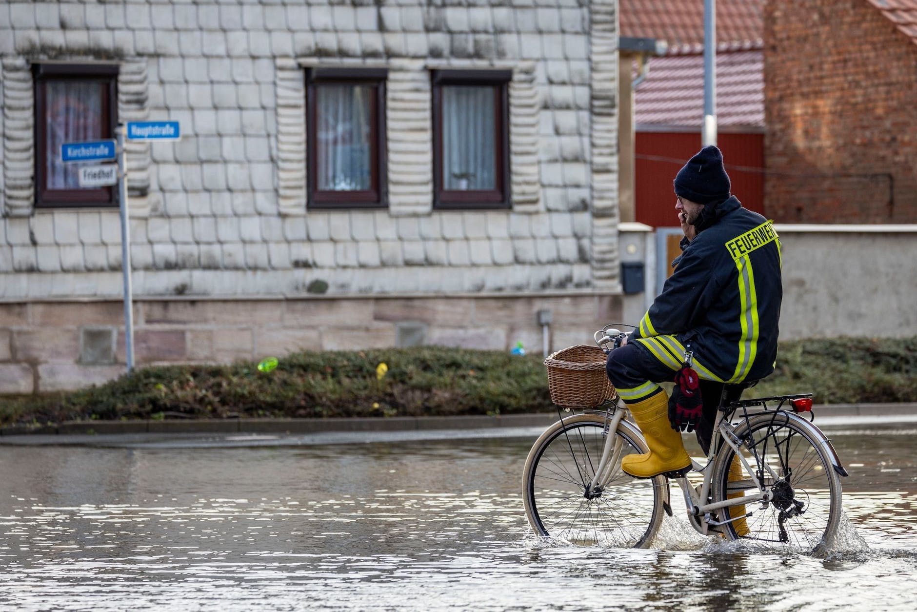 A firefighter on a bicycle in a flooded street in Windehausen.