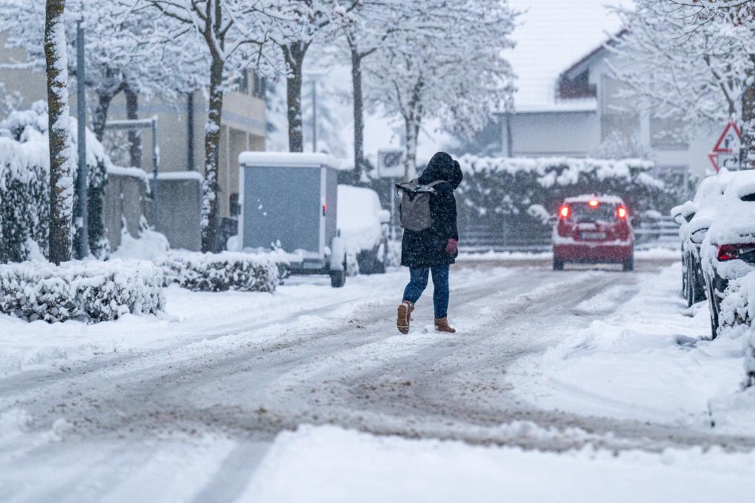 Eine Frau geht auf einer mit Schnee bedeckten Straße