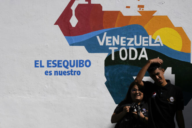 “Essequibo is ours.”  A couple poses in Caracas, on November 29, 2023, in front of a fresco representing a map of Venezuela, including the Essequibo region, today officially attached to Guyana.