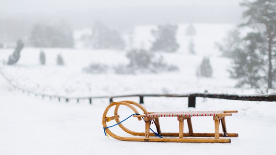 A wooden sleigh in front of a snowy winter landscape in the Büsenbachtal near Buchholz in the Nordheide.  © Alexander Cornelius Mühlhausen 