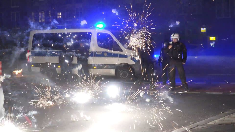 Police officers stand in front of exploding fireworks.  In many places there is a ban on firecrackers on New Year's Eve
