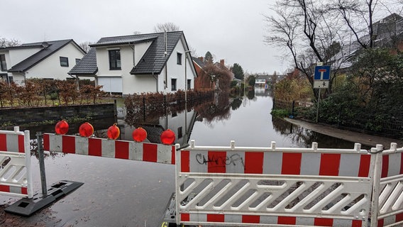 Eine Straße in einem Wohngebiet in Lilienthal steht unter Wasser. © NDR Foto: Sebastian Duden