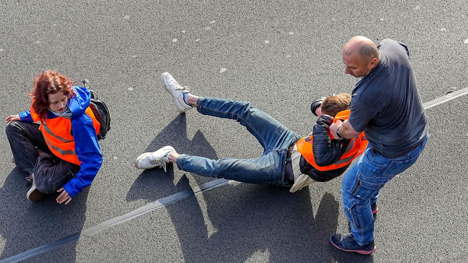 Climate activists block a road and a man tries to drag one off the road