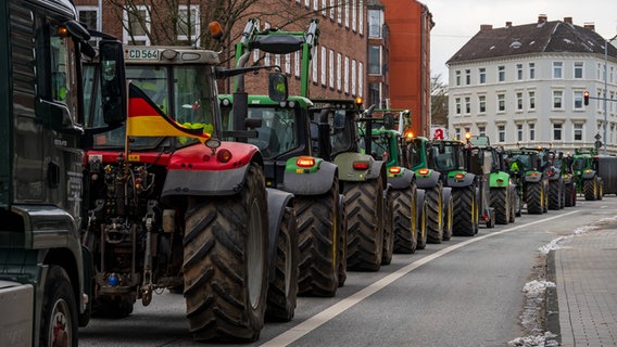 A column of tractors drives through a street in Kiel.  © IMAGO / penofoto 