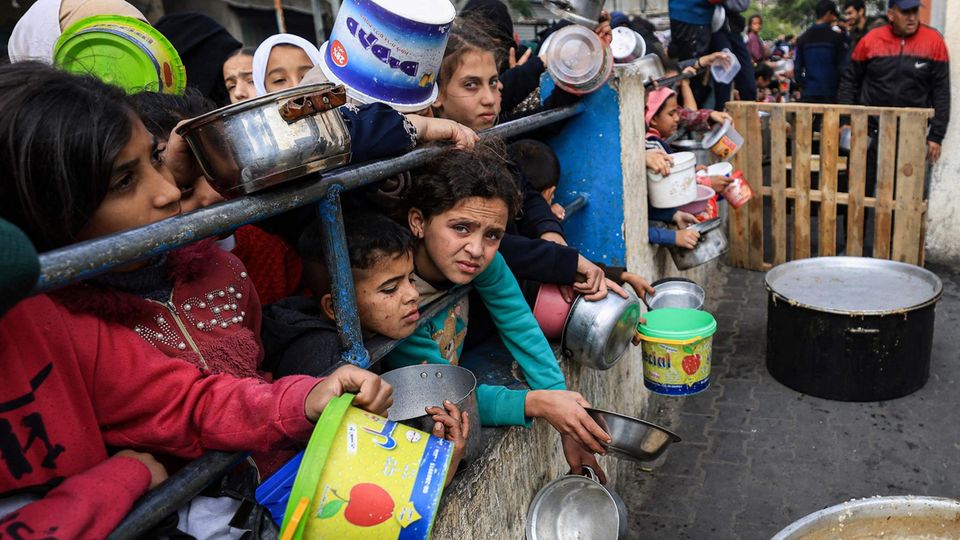 Palestinian children wait for some food at a distribution point in Rafah.