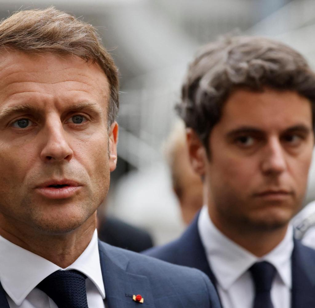 French Education and Youth Minister Gabriel Attal (R) watches French President Emmanuel Macron as he talks to the press after a visit to the Gambetta high school in Arras, northeastern France on October 13, 2023, after a teacher was killed and two other people severely wounded in a knife attack.  A man of Chechen origin stabbed to death a teacher and severely wounded two other adults on October 13 at a school in northeastern France, with prosectors opening a probe into a suspected act of terror.  (Photo by Ludovic MARIN / POOL / AFP)
