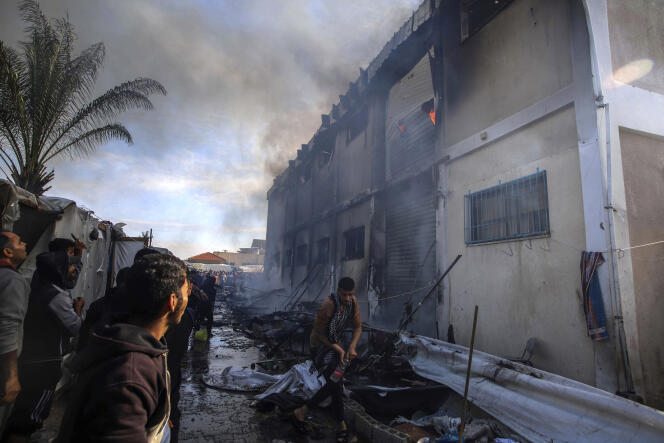 Palestinians try to put out a fire at an UNRWA building, which displaced people are using as shelter, after it was targeted by Israeli tanks in Khan Younes, southern Gaza Strip, on January 24 2024. 