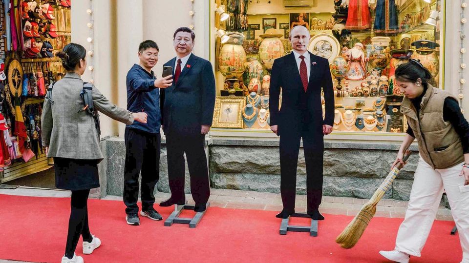 Tourists pose with cardboard cutouts of the two heads of state Xi and Putin in Moscow in May 2023