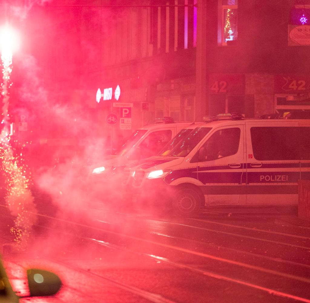 Auf der Wanheimer Straße in Duisburg wird Feuerwerk gezündet, Fahrzeuge der Polizei stehen bereit