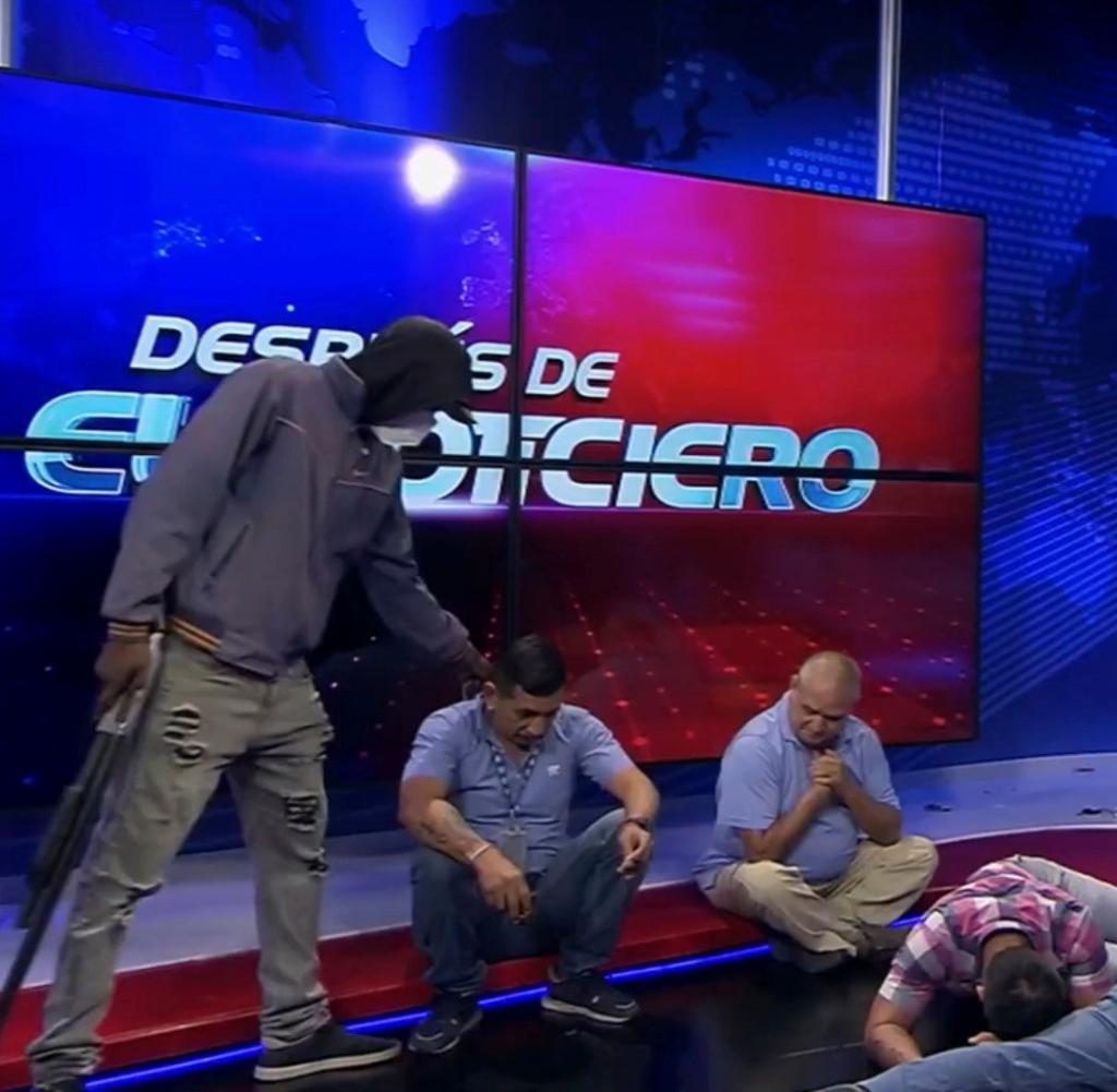 This screenshot from a live broadcast on TC Television shows one of the masked, armed people and journalists