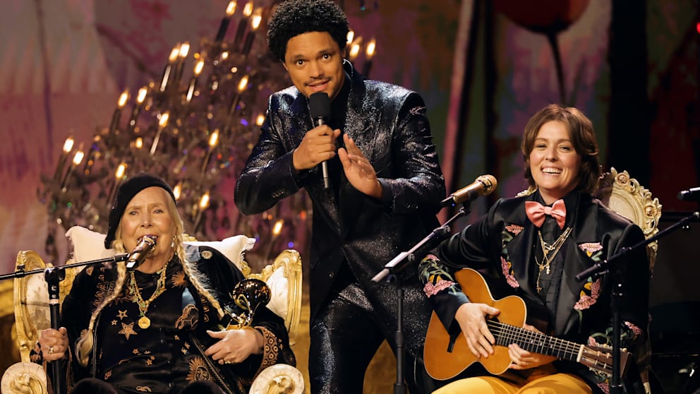 Joni Mitchell (80, left) sang one of her most beautiful songs “Both Sides, Now” together with Brandi Carlile.  Moderator Trevor Noah (center) was blown away