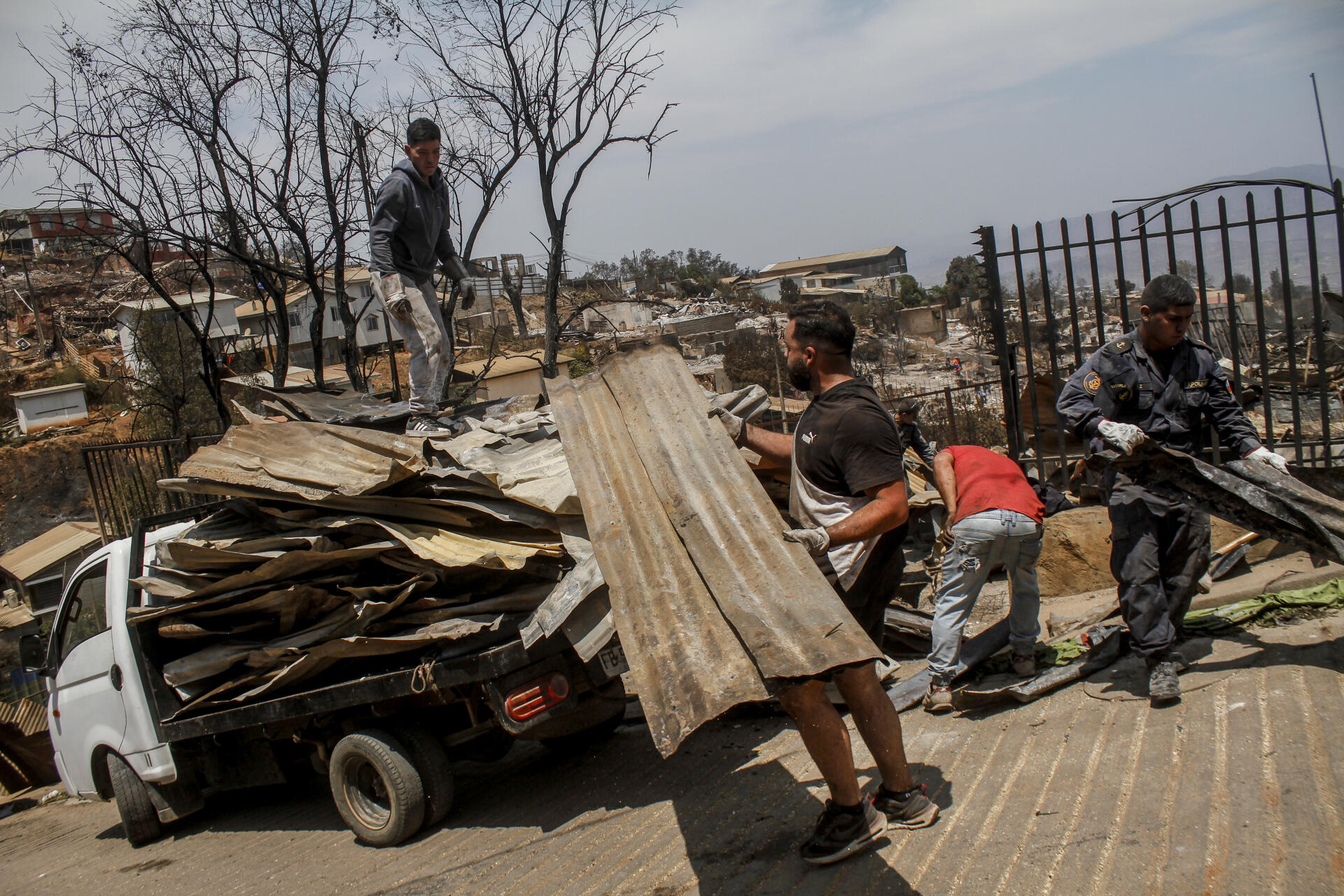 Residents clean up the rubble of burned houses after forest fires reached their neighborhood, in Vina del Mar, Chile, Sunday February 4, 2024.