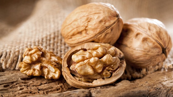 Closed and opened walnuts on a piece of wood.  © fotolia Photo: karepa